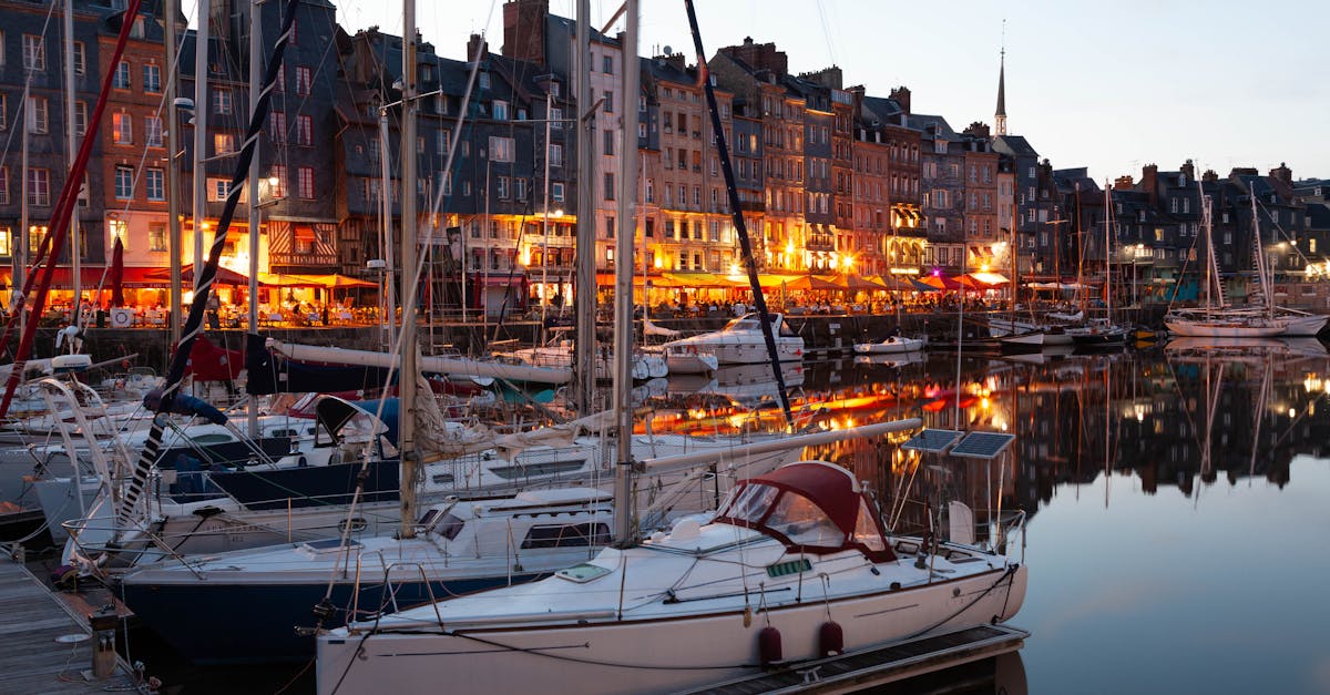 Beautiful evening view of yachts moored in Honfleur harbor reflecting colorful buildings.