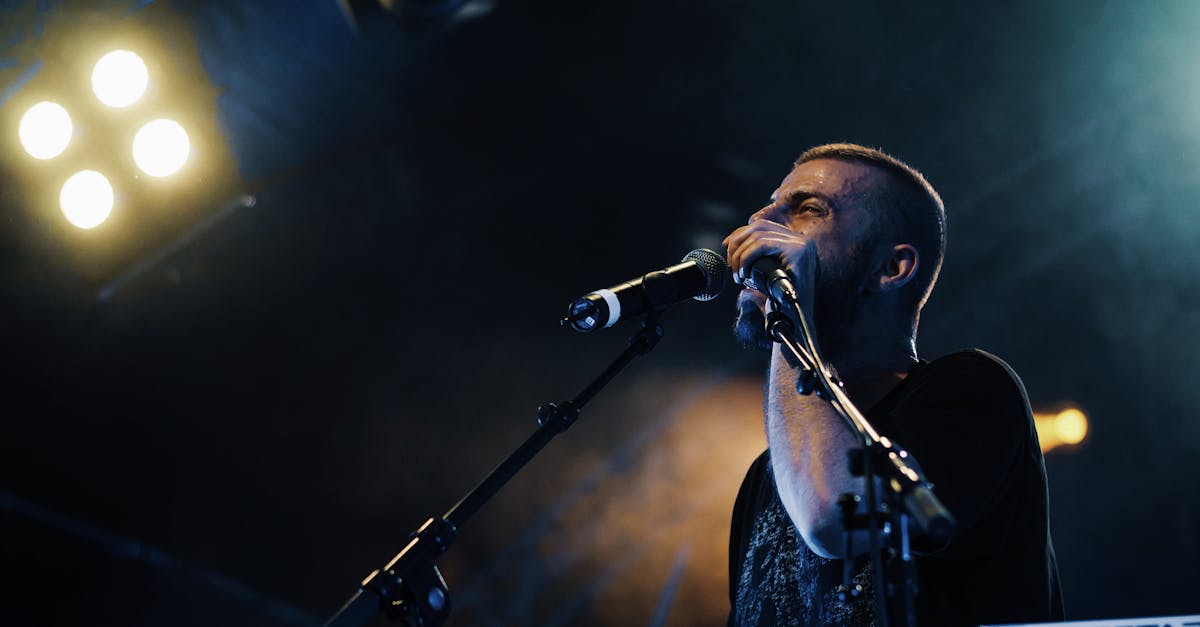 A dynamic live concert performance of a male singer with band under bright stage lights.
